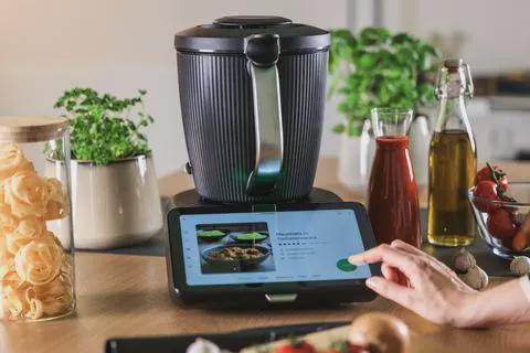A hand tapping the Thermomix TM7 touchscreen
